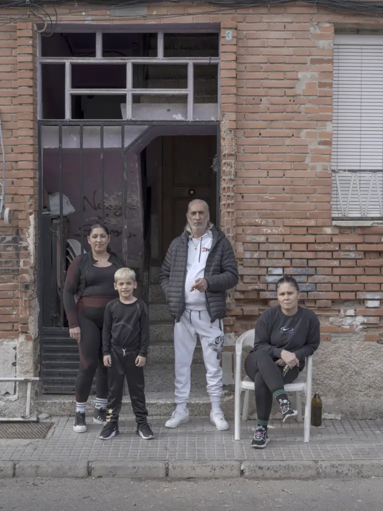 Tres adultos y un niño posando frente a la puerta de una casa de ladrillo visto.
